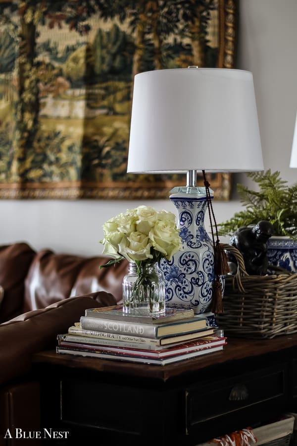 A glass vase with roses styled atop stacked books for a focal point in a lived-in home