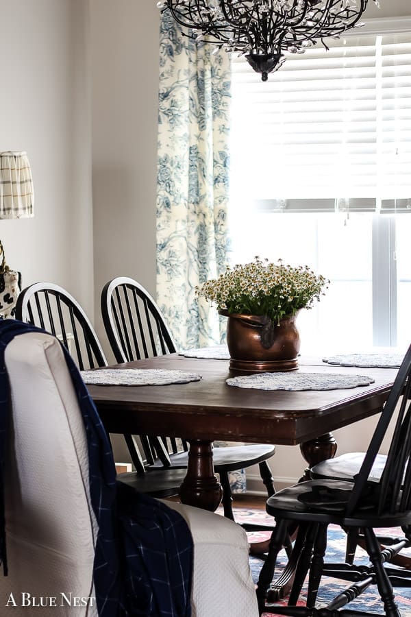 A vintage dining table styled with an antique copper pot full of flowers.